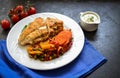 Baked chicken breast with vegetables. Chicken breast, asparagus, carrots, in a white plate. Dark background. Free space for text.