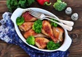 Baked chicken drumstick with organic broccoli on a wooden background. Royalty Free Stock Photo