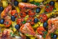 Baked chicken drumsticks, closeup. Cooked with cherry tomatoes, black olives, rosemary and potatoes