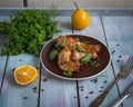 Baked chicken drumsticks with fresh parsley sprigs on a brown plate on a plain wooden tray Royalty Free Stock Photo