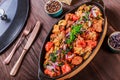 Baked chicken with grilled vegetables, greens, lavash in pan on wooden table.