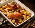 Baked chicken leg quarters  seasoned with garlic and herbs with potatoes in a baking dish on a wooden tabl Royalty Free Stock Photo