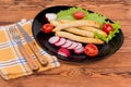 Baked chicken sausages with greens and vegetables, fork and knife Royalty Free Stock Photo