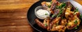 Baked chicken wings in Mexican with curry seasoning and parsley on a black plate, on a wooden background. side view, copy space Royalty Free Stock Photo