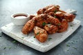 Baked chicken wings with sesame seeds and sweet chili sauce on white wooden board.