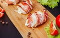 Baked chicken wrapped in bacon. Delicious appetizer with crispy smoked bacon. Chicken breast wrapped in bacon on wooden board. Royalty Free Stock Photo