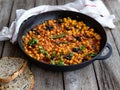 Baked chickpea Baked chickpea with vegetables, olives and sundried tomatoes in iron pan, frying pan on wooden table Royalty Free Stock Photo