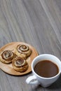 Baked cinnamon burgers. Lie on a plate. Nearby is a cup of coffee