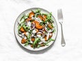 Baked crispy sweet potatoes, arugula, red onion and yogurt mustard dressing salad on a light background, top view