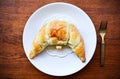 Baked croissant in white plate with fork on wood table concept background Royalty Free Stock Photo