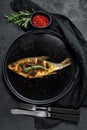 Baked crucian carp on a white plate. River  organic fish. Black background. Top view Royalty Free Stock Photo