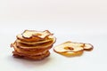 Baked dehydrated apple slices stacked on white wooden table. Homemade dry fruit chips, autumn fall snack, healthy vegan food