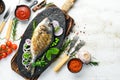 Baked Dorado fish with vegetables on a black stone plate. Top view.