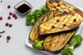 Baked eggplant with with parsley and broccoli. Sauce in bowl and cranberries on table