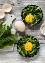 Baked eggs with spinach on a light wooden background