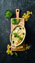 Baked farfalle pasta with salmon and cheese in a bowl on a black stone background. Top view. Rustic style