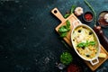 Baked farfalle pasta with salmon and cheese in a bowl on a black stone background. Top view. Rustic style