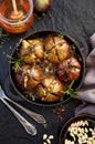 Baked figs stuffed with gorgonzola cheese, pine nuts, honey and herbs in a black dish on a dark, stone background, top view.