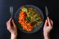 Baked fish flounder with carrot and spicy herbs, closeup on black background. Delicious fish dish with vegetables for healthy and