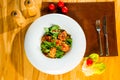 Baked fish on a plate dressed with sauce and decorated with fresh herbs