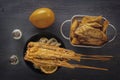 Baked fish on skewers in a black plate, french fries and lemon on a wooden table. Royalty Free Stock Photo