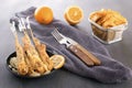 Baked fish on skewers in a black plate, french fries and lemon on a wooden table. Royalty Free Stock Photo