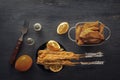 Baked fish on skewers in a black plate, french fries and lemon on a wooden table. Royalty Free Stock Photo