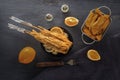 Baked fish on skewers in a black plate, french fries and lemon on a wooden table. Royalty Free Stock Photo