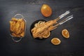 Baked fish on skewers in a black plate, french fries and lemon on a wooden table. Royalty Free Stock Photo