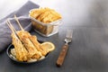 Baked fish on skewers in a black plate and french fries on a wooden table. Royalty Free Stock Photo