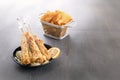 Baked fish on skewers in a black plate and french fries on a wooden table. Royalty Free Stock Photo