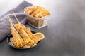 Baked fish on skewers in a black plate and french fries on a wooden table. Royalty Free Stock Photo