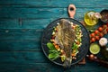 Baked Flounder Fish with Vegetables on a Black Stone Plate. Seafood. Top view.