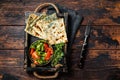 Baked Gozleme flatbread with greens in a box with vegetable salad. Wooden background. Top view