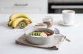 Baked granola with banana and kiwi on the table with cup of tea on a white kitchen background