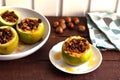 Baked green apples with nuts and raisins on a white plate on a brown wooden table Royalty Free Stock Photo