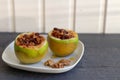 Baked green apples with nuts and raisins on a white plate on a grey wooden table Royalty Free Stock Photo