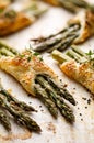 Baked green asparagus in puff pastry sprinkled with sesame seeds, nigella seeds and fresh thyme on a white background, close-up, t Royalty Free Stock Photo