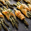 Baked green asparagus in puff pastry sprinkled with sesame seeds, nigella seeds and fresh thyme on a black background, close-up, t Royalty Free Stock Photo