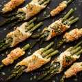 Baked green asparagus in puff pastry sprinkled with sesame seeds, nigella seeds and fresh thyme on a black background, close-up, t Royalty Free Stock Photo