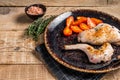 Baked hare legs on a plate with tomato. Wooden background. Top view. Copy space