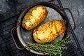 Baked hasselback potatoes with cheese, garlic, thyme and rosemary. Black background. Top view Royalty Free Stock Photo