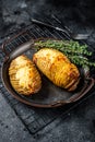 Baked hasselback potatoes with cheese, garlic, thyme and rosemary. Black background. Top view Royalty Free Stock Photo