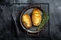 Baked hasselback potatoes with cheese, garlic, thyme and rosemary. Black background. Top view Royalty Free Stock Photo