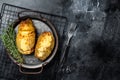 Baked hasselback potatoes with cheese, garlic, thyme and rosemary. Black background. Top view. Copy space Royalty Free Stock Photo