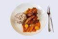 Baked hen with carot and kumquat, rice with quinoa on white plate on white backround