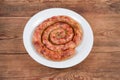 Baked homemade pork sausage curtailed by spiral on white dish Royalty Free Stock Photo