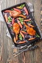 Baked honey pork chops with red onion and rhubarb close-up in a baking sheet. Vertical top view