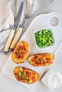 Baked loaded potato skins with cheddar cheese and bacon on a ceramic plate, garnished with scallions and sour cream, vertical, top Royalty Free Stock Photo