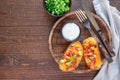 Baked loaded potato skins with cheddar cheese and bacon on wooden plate, garnished with scallions and sour cream, horizontal, top Royalty Free Stock Photo